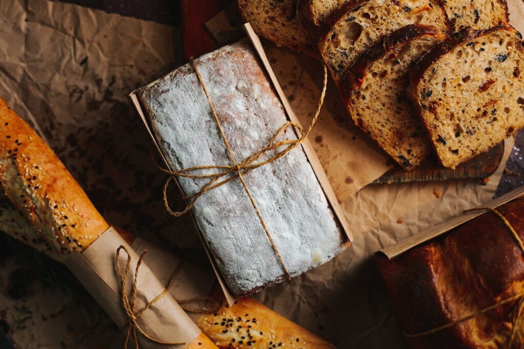 pexels-photo-14565950 A top view of various fresh artisan bread includes sliced bread and wrapped baguettes.