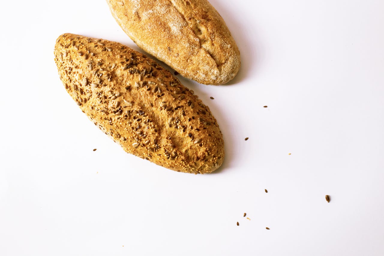 about-us-02 Two artisan loaves of bread with seeds, showcasing fresh baking, on a clean white backdrop.