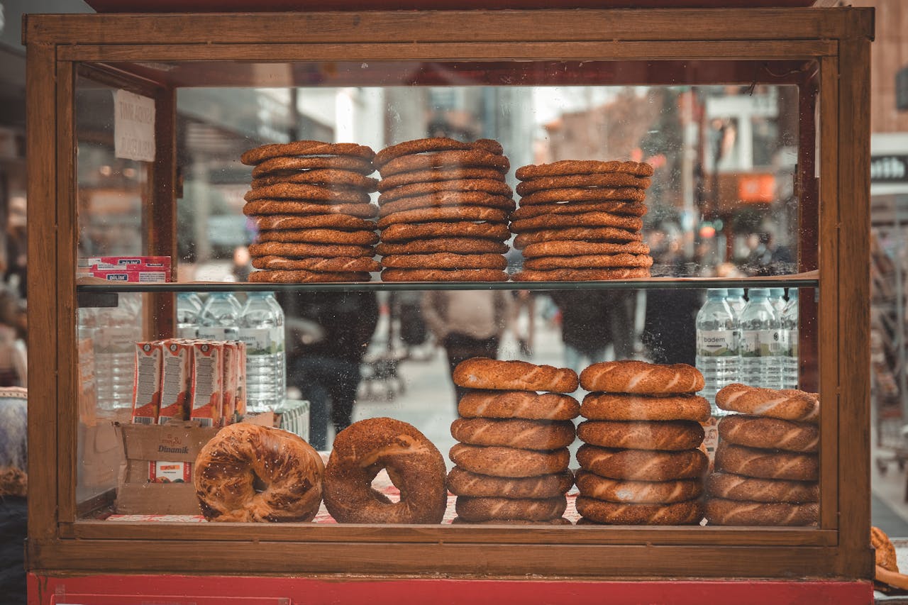 Turkish street vendor stall displaying fresh simit bagels on a bustling city street.