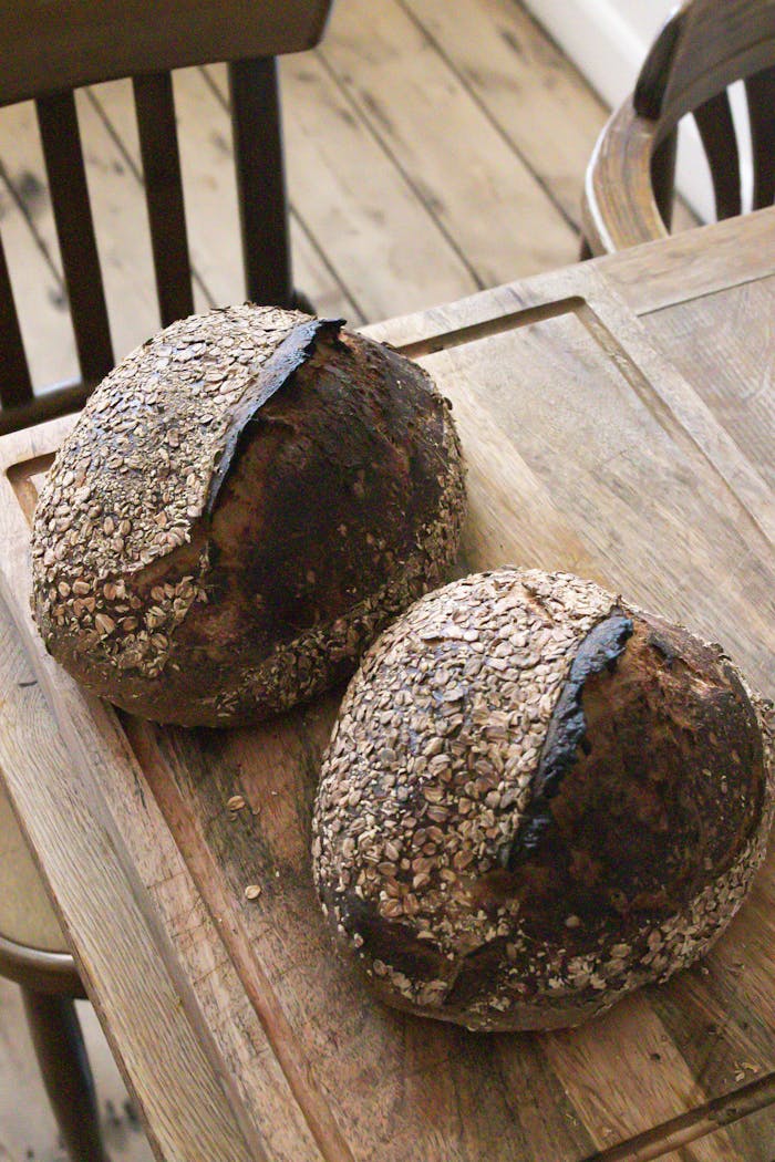 Freshly baked sourdough bread loaves with oats on a rustic wooden table.